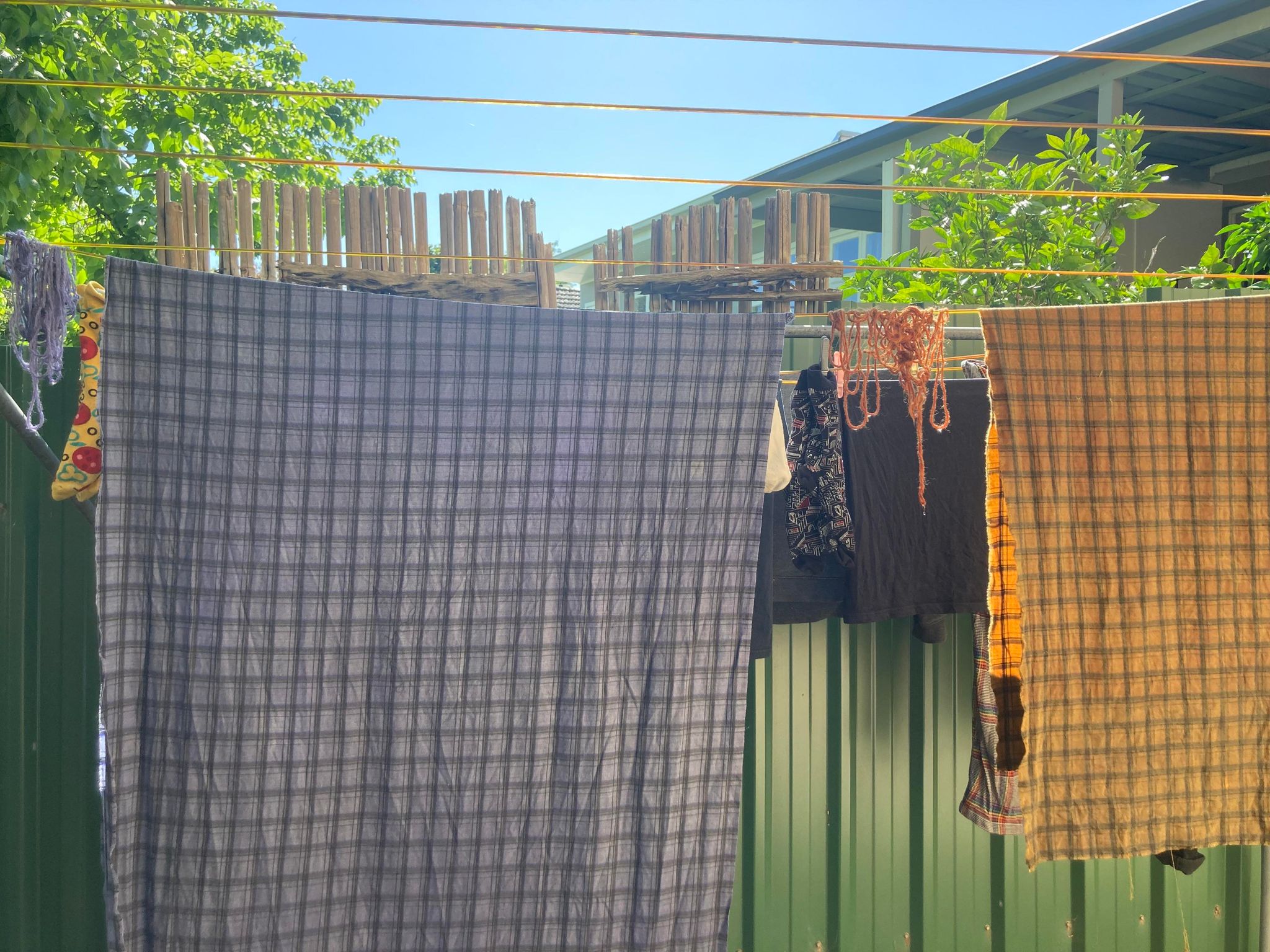 Plaid orange and blue fabric and yarn drying on a washing line.